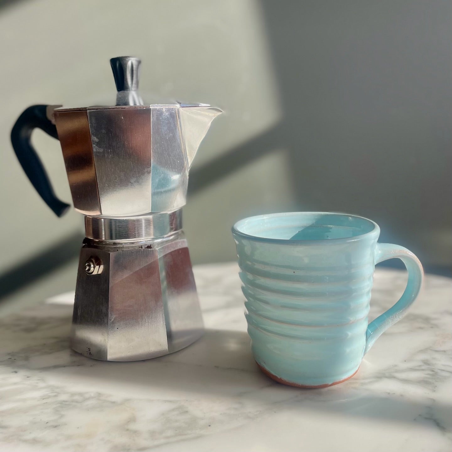 White mug with coffee on a windowsill with a blurred outdoor view