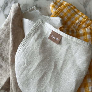 Set of folded linen napkins with a brand tag on a marble surface