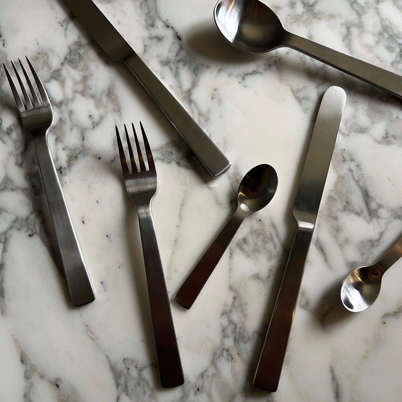 Stainless steel cutlery set on a marble surface