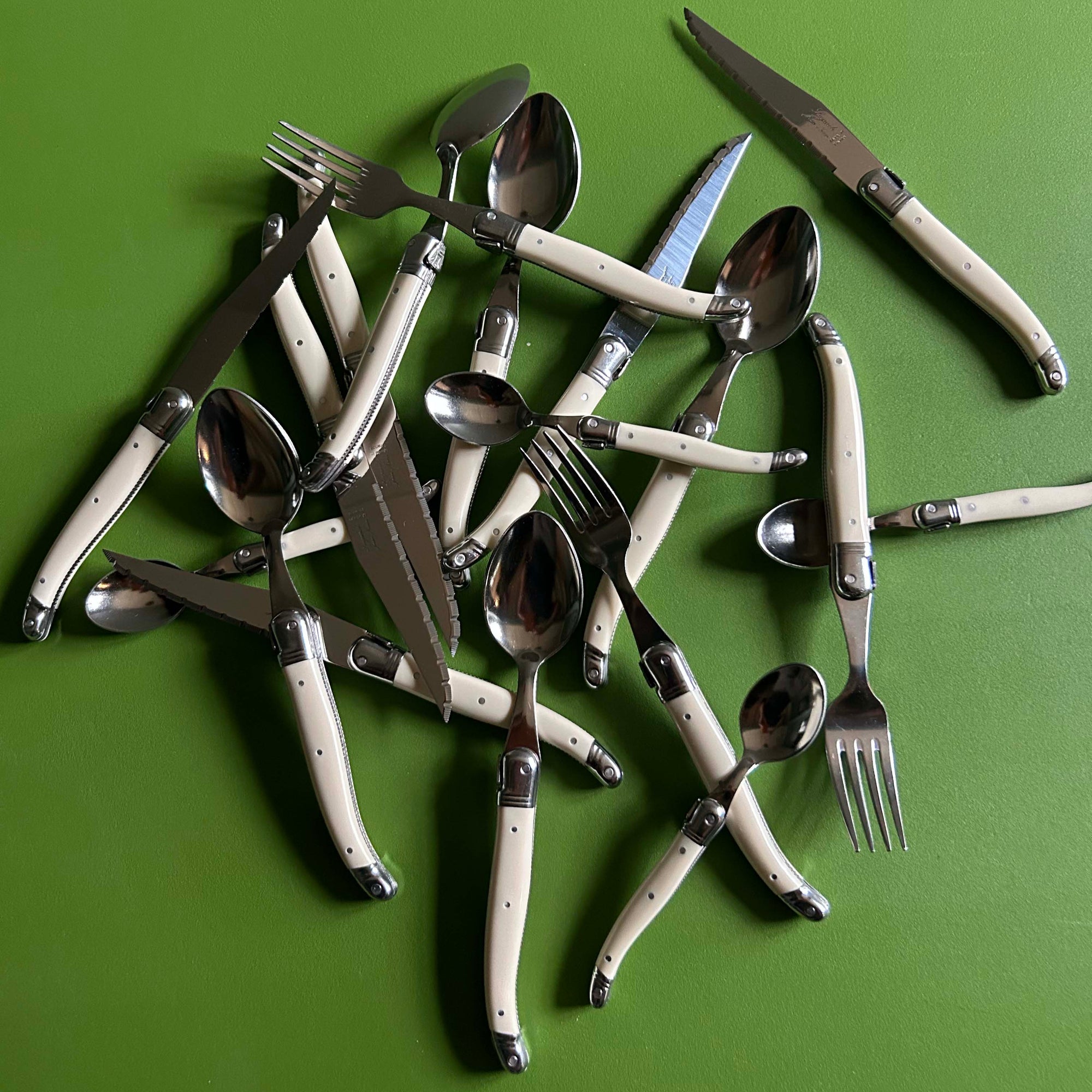 Set of silverware including forks, knives, and spoons on a green background